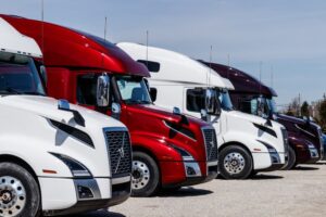 Diverse array of Volvo semi tractor-trailer trucks showcased in a lineup available for purchase, displaying vibrant colors.