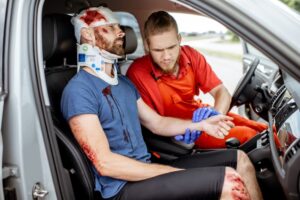 Medic attends to seriously injured man in car after road accident, offering urgent medical aid.