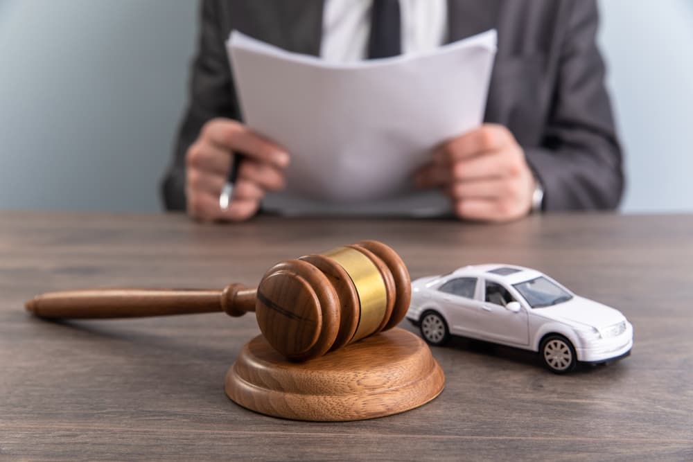 A model of a car and a gavel, representing an accident lawsuit or insurance claim.