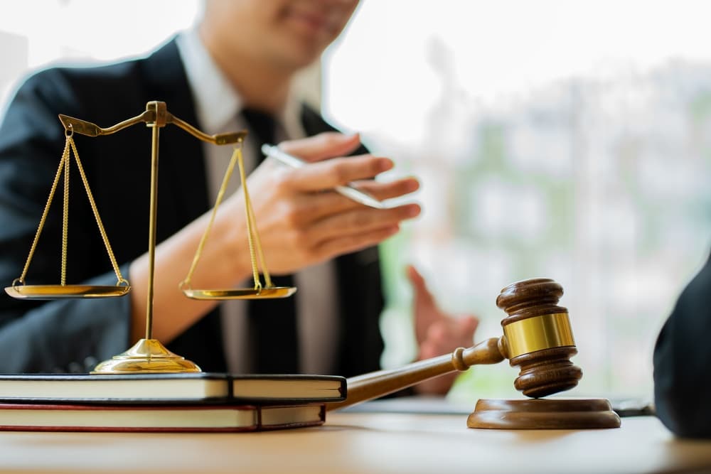 A lawyer working at the desk with a gavel and scales of justice on the table.






