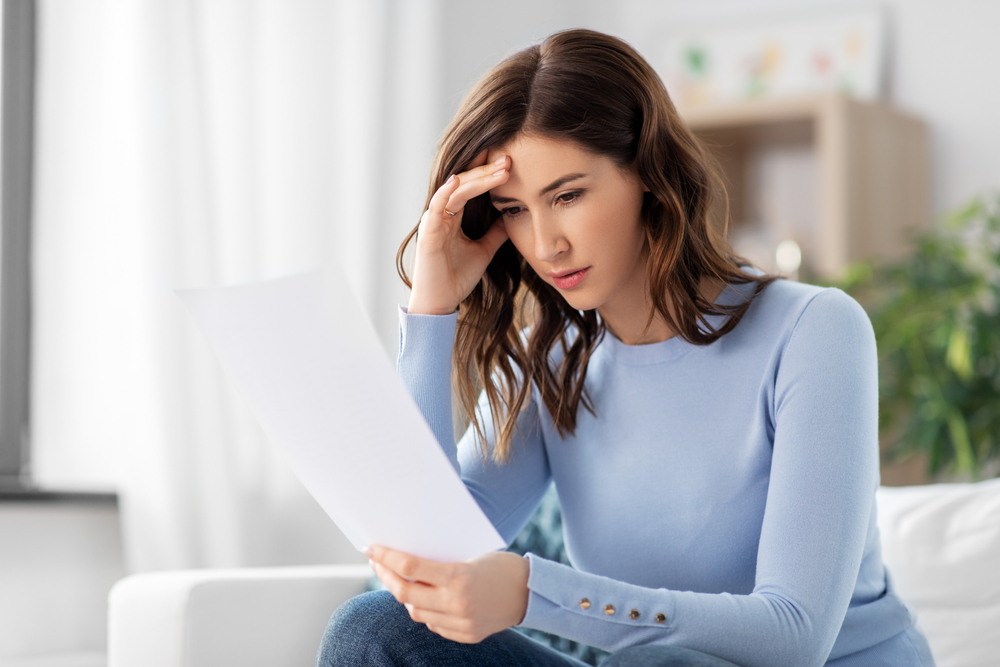 stressed woman with paper sheet at home.