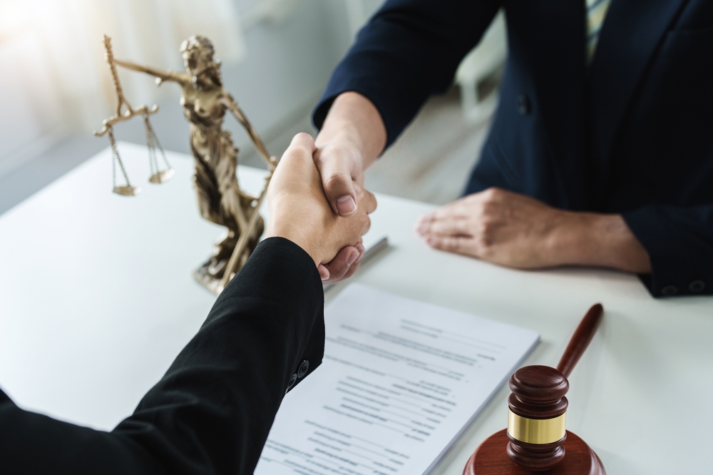 lawyer or attorney shakes hands to agree on the client's offer to be hired to fight the parties in court