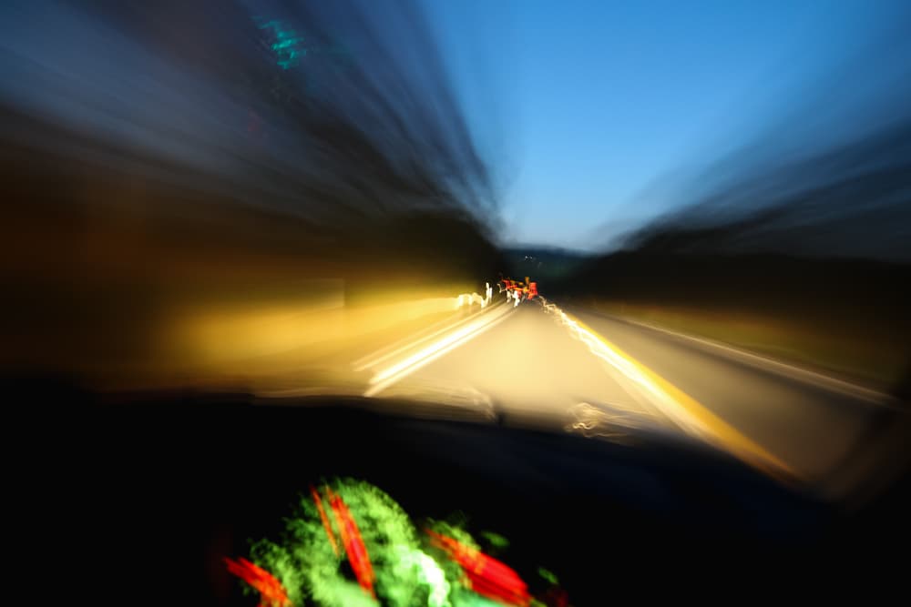 A blurred view from inside a moving car at night, depicting speed and motion on the road.