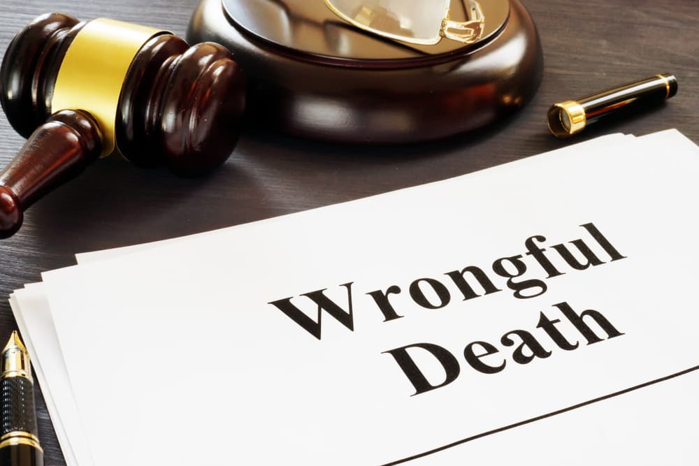 A gavel, pen, and a document titled "Wrongful Death" on a wooden desk.