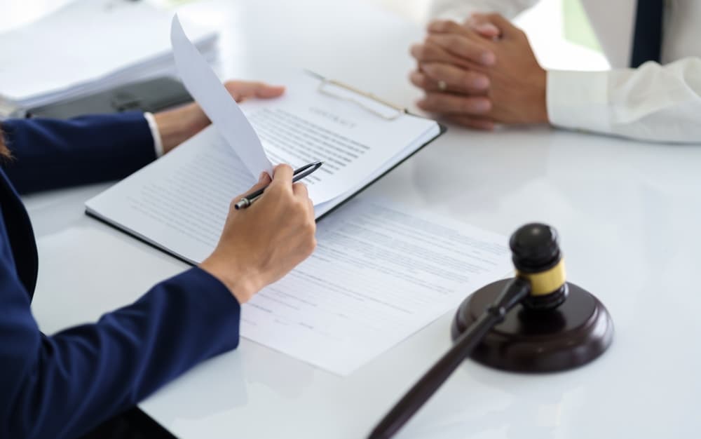 A lawyer reviewing legal documents with a client at a desk, featuring a gavel.