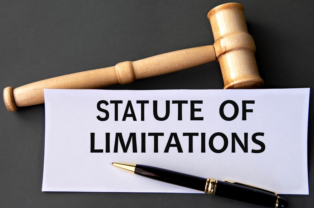 A gavel and a pen placed on a paper labeled "Statute of Limitations" on a dark background.