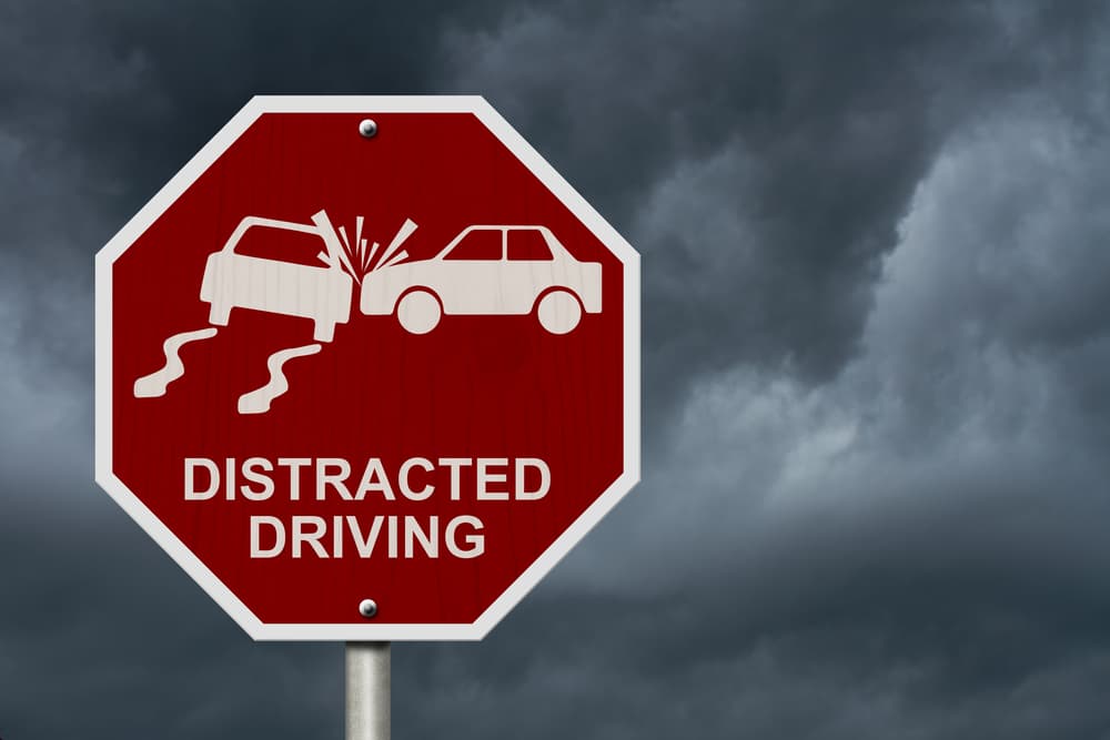 No Distracted Driving Sign, Red stop sign with words Distracted Driving and accident icon with stormy sky background
