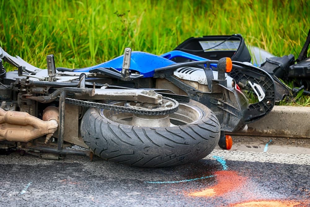 A crashed motorcycle lying on the road after an accident, with visible damage to the vehicle.